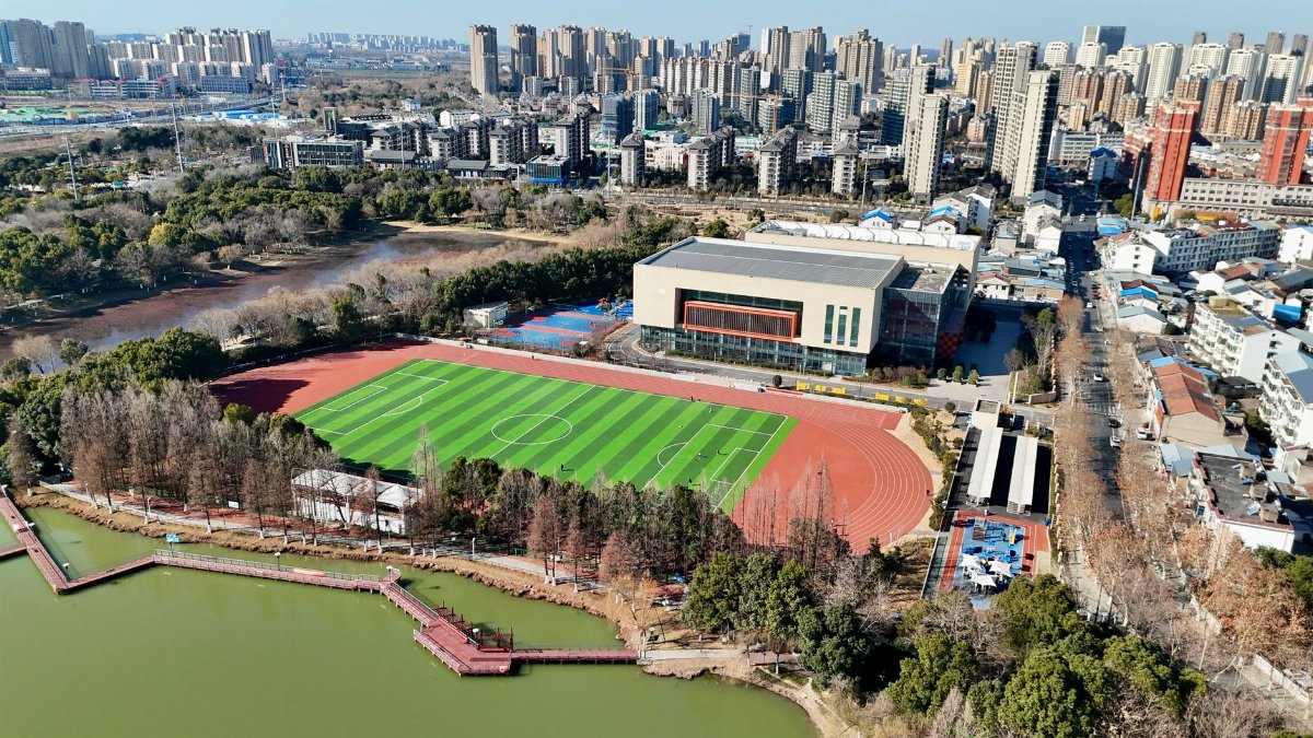 Aerial image of a city park with a sports field and surrounding buildings.