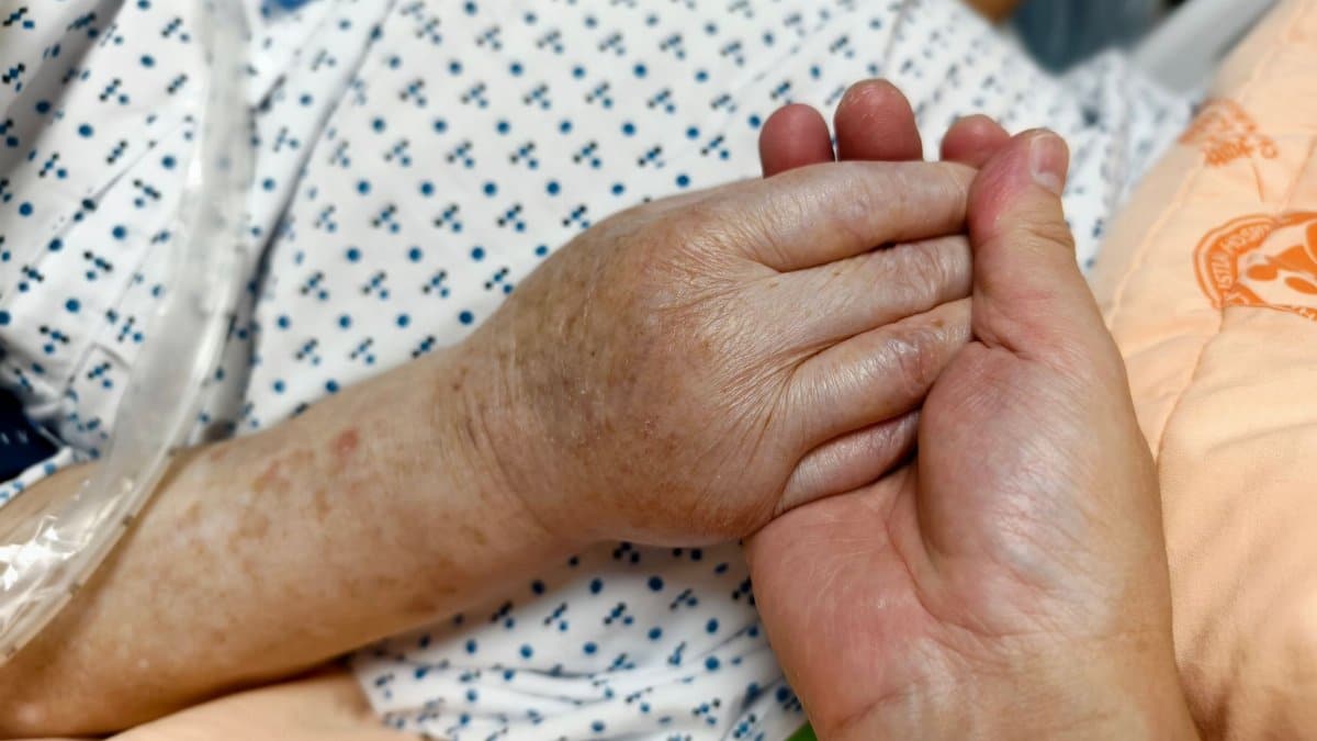 Close-up of hands holding in a hospital setting, symbolizing compassion and care.