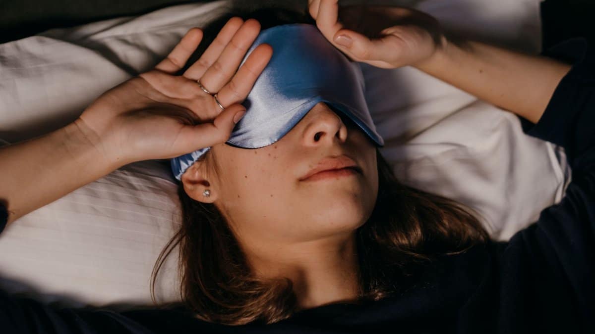 A woman peacefully resting with a sleep mask in a cozy indoor setting.