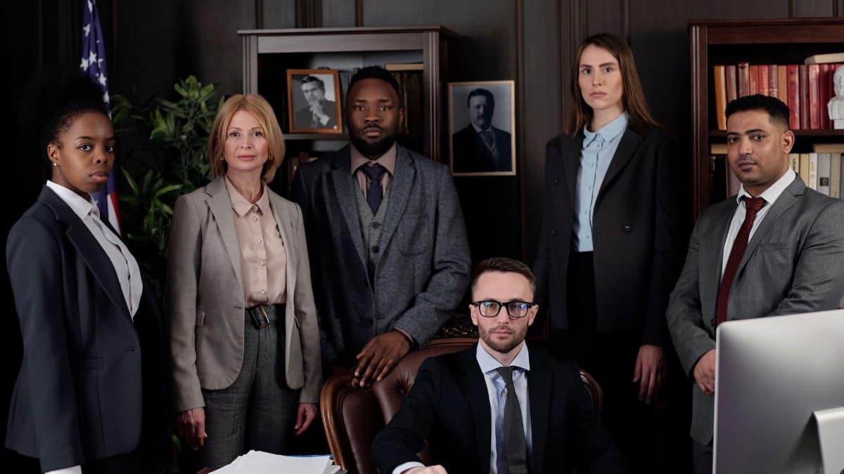 A diverse group of business professionals posing in an office, showcasing teamwork and leadership.