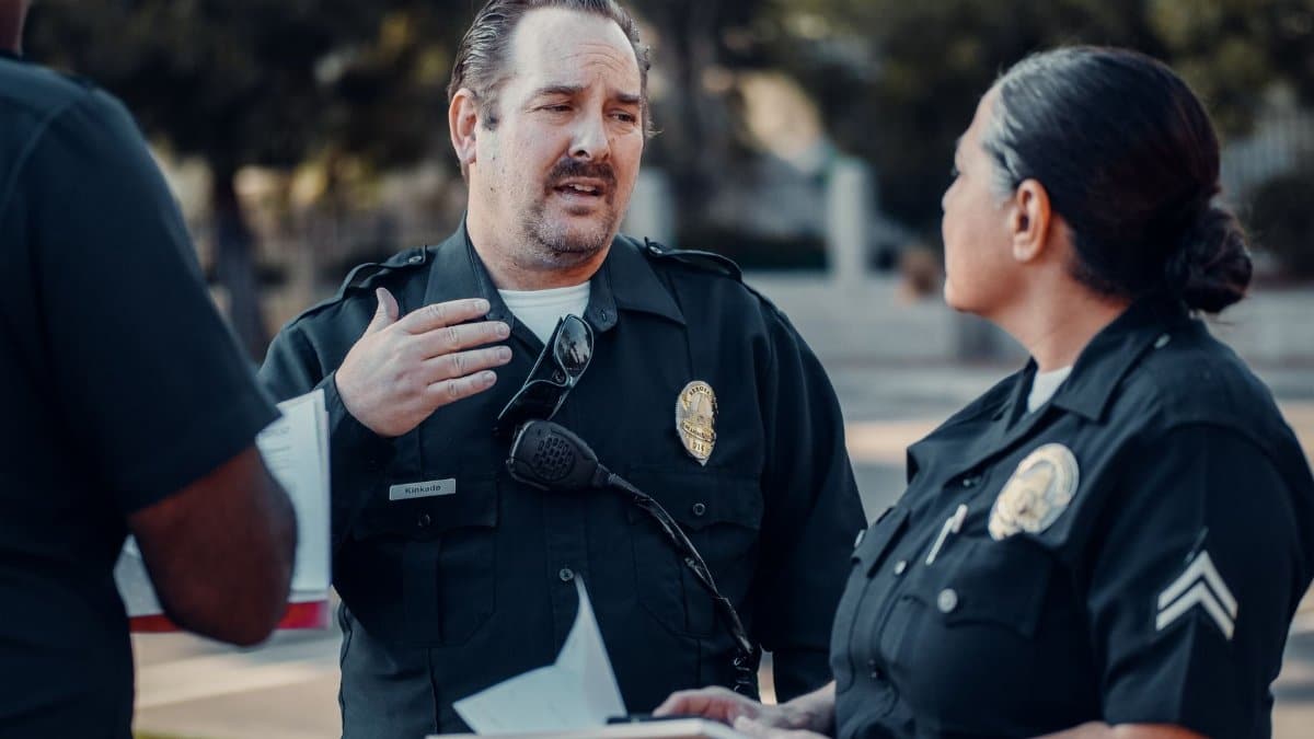 Three police officers engage in conversation outdoors, showcasing teamwork.