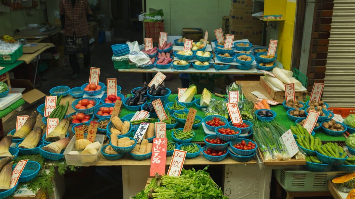 Japanese trader selling fresh tomatoes and other fresh vegetables to customers in the street market