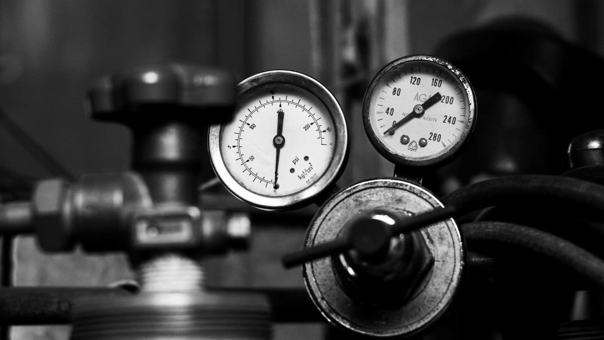 A detailed monochrome image of vintage industrial pressure gauges with metal pipes.