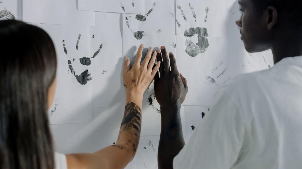 Two individuals creating art with handprints on a wall, symbolizing creativity and unity.