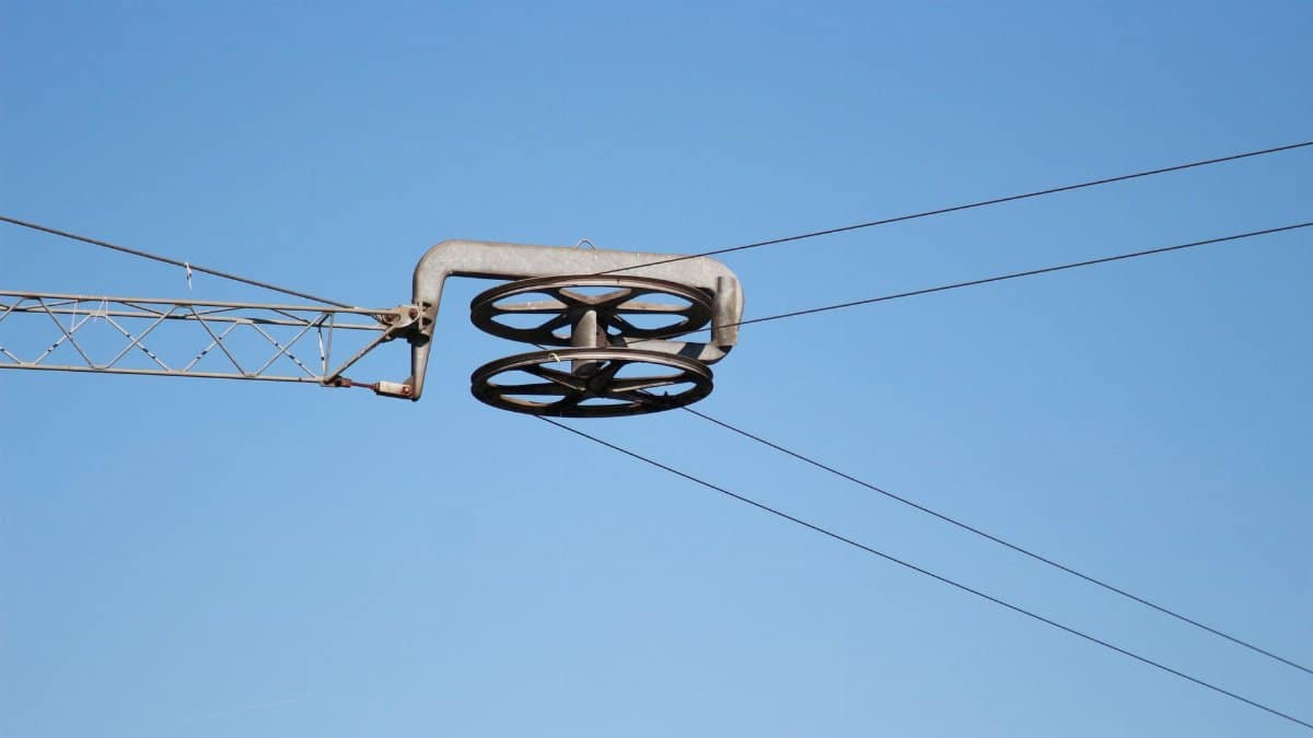 Close-up of an industrial cable pulley system against a clear blue sky.