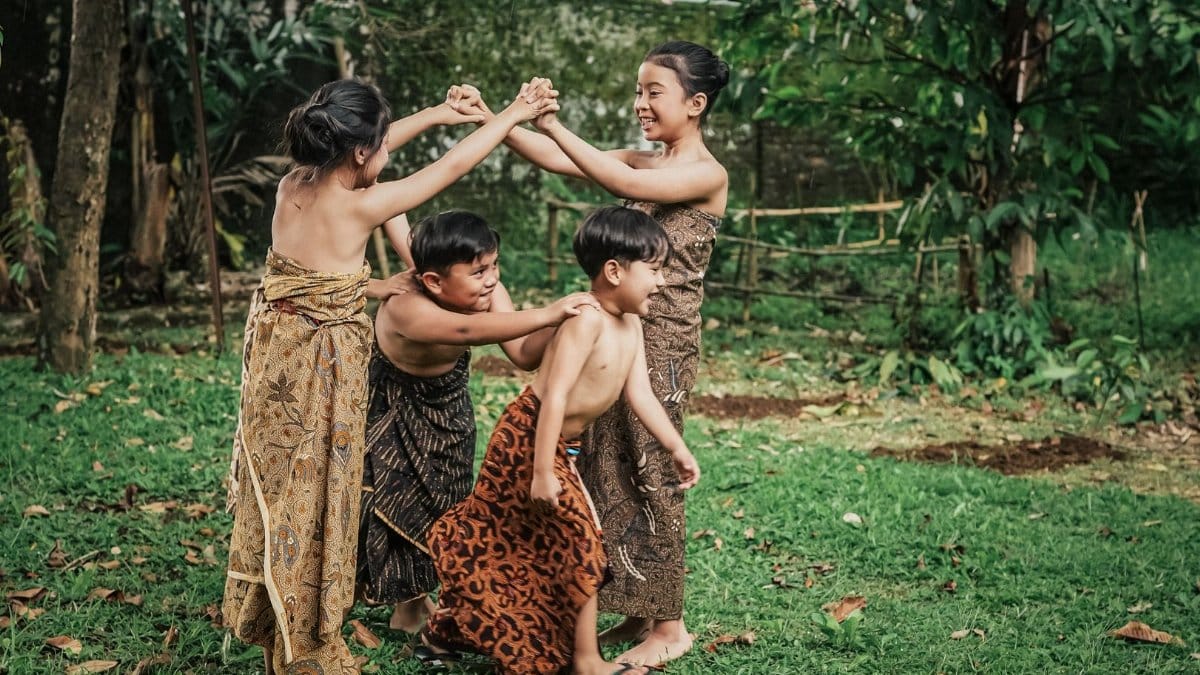 Children in traditional Indonesian attire play a classic game outdoors, showcasing cultural heritage and joyful expression.