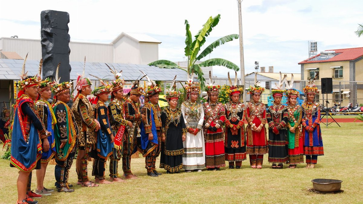 Group of people in colorful traditional attire standing outdoors during a cultural ceremony.