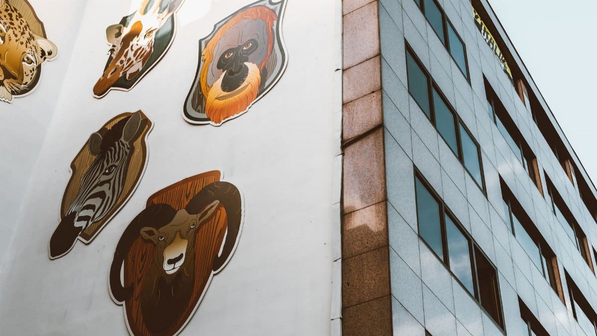 Creative animal mural displayed on the side of a city skyscraper, featuring diverse wildlife.