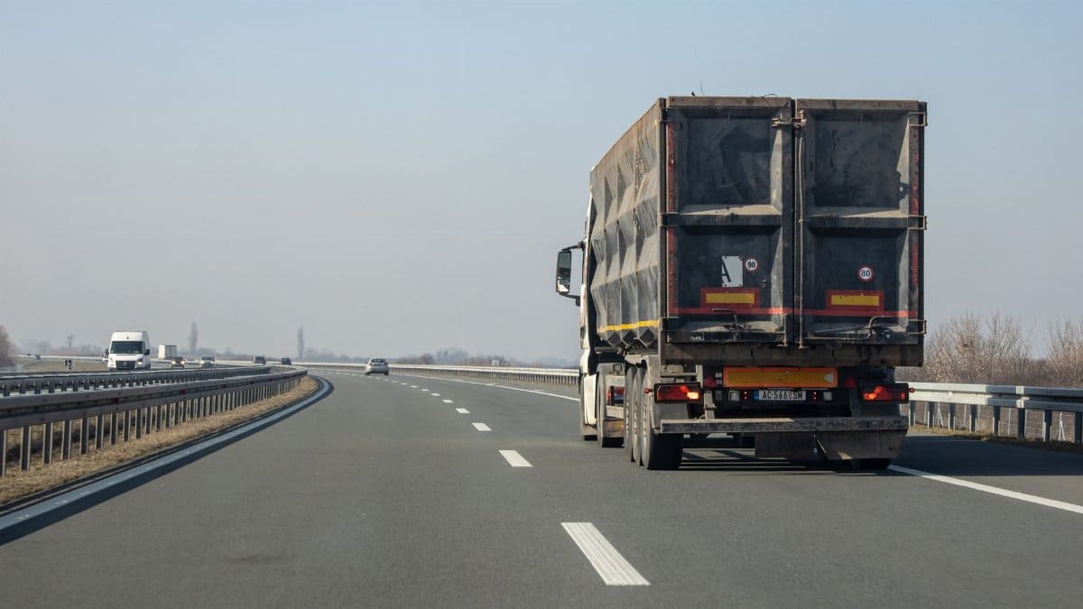 A cargo truck travels down an empty highway on a clear day, showcasing transportation and logistics.