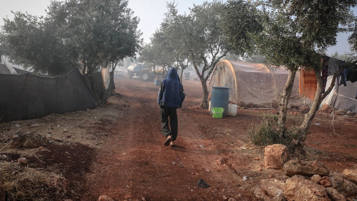 A person walks through a refugee camp in Idlib, Syria, showcasing daily life.