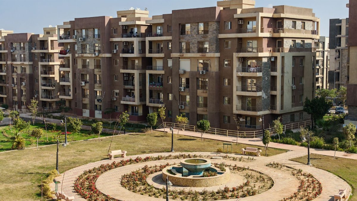 View of a modern apartment complex with a central garden featuring a fountain.