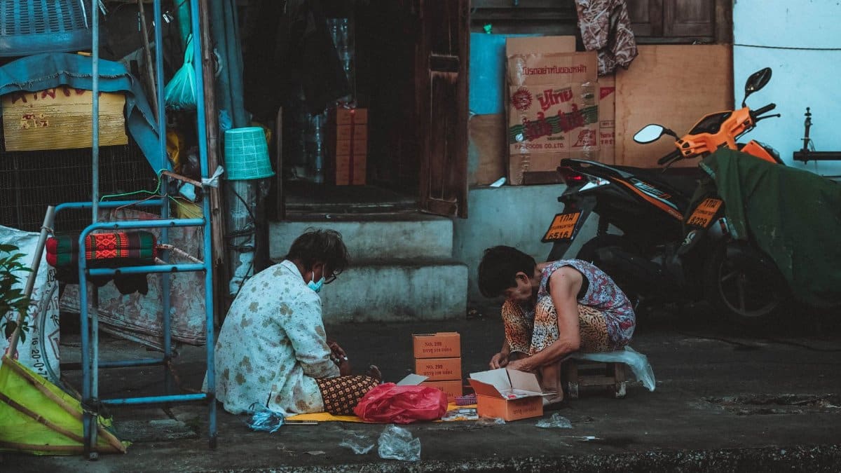 Two people engaged in daily activities on a street in vibrant Bangkok, Thailand.
