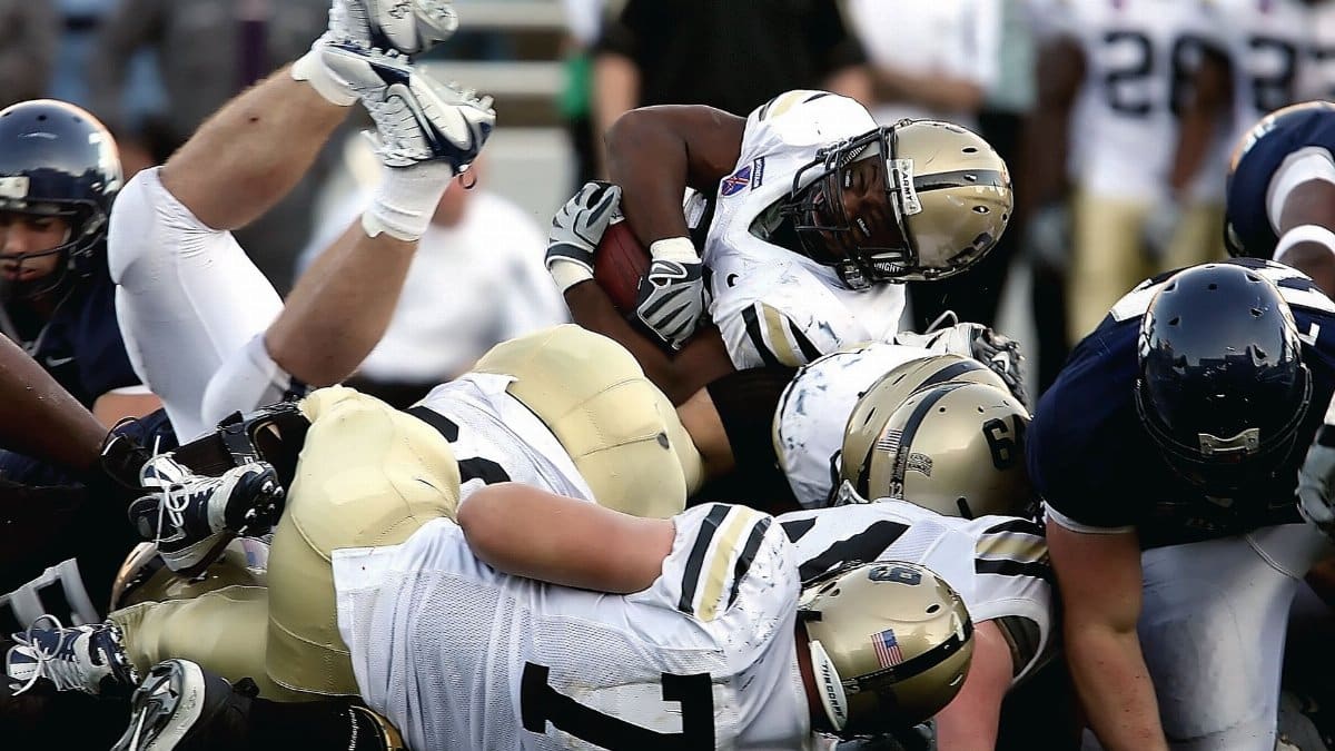 Intense action scene of football players tackling during a game, showcasing teamwork and sportsmanship.