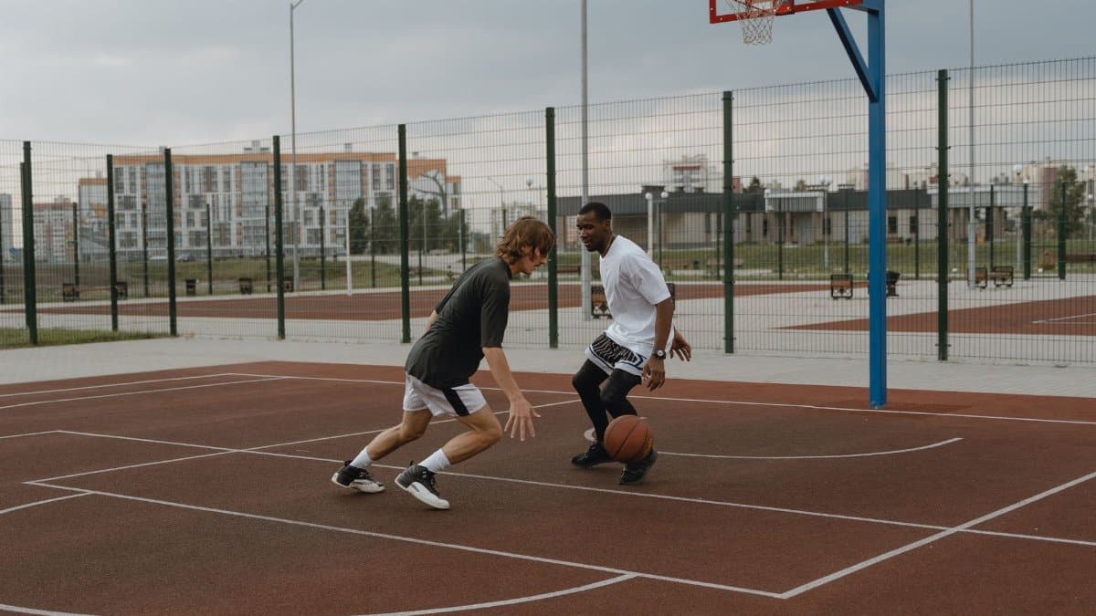 Two men engaging in a friendly basketball game on an outdoor court.