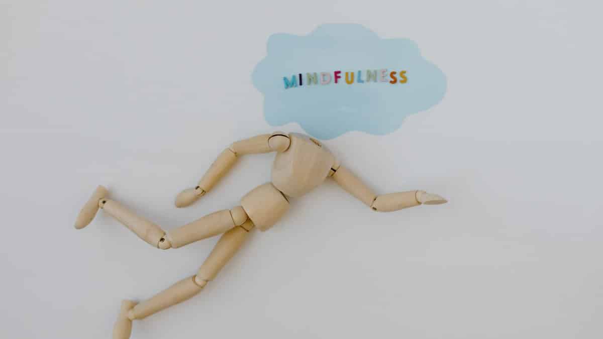 Wooden mannequin with speech bubble highlighting mindfulness concept on white background.