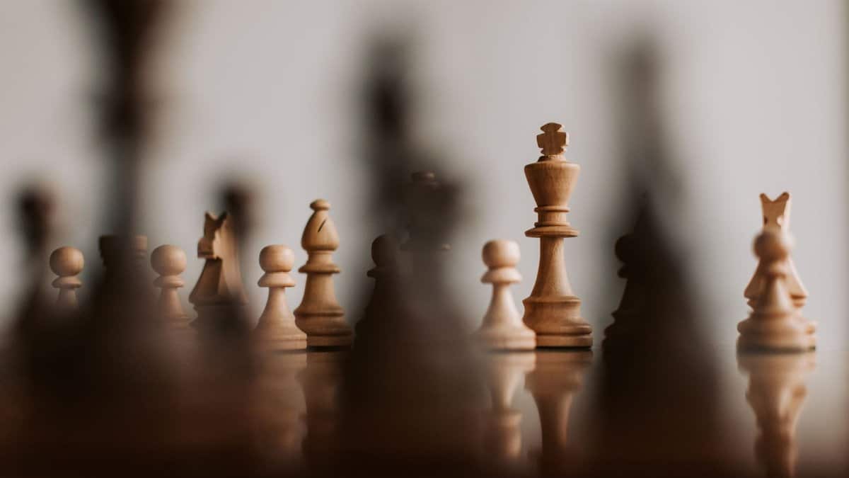 Close-up view of a chessboard with wooden pieces focusing on king, showcasing strategy and depth of field.
