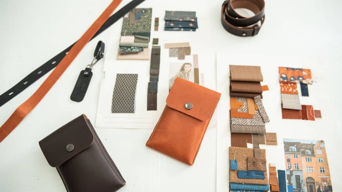 A modern workspace showcasing leather accessories and fabric moodboards for fashion design inspiration.