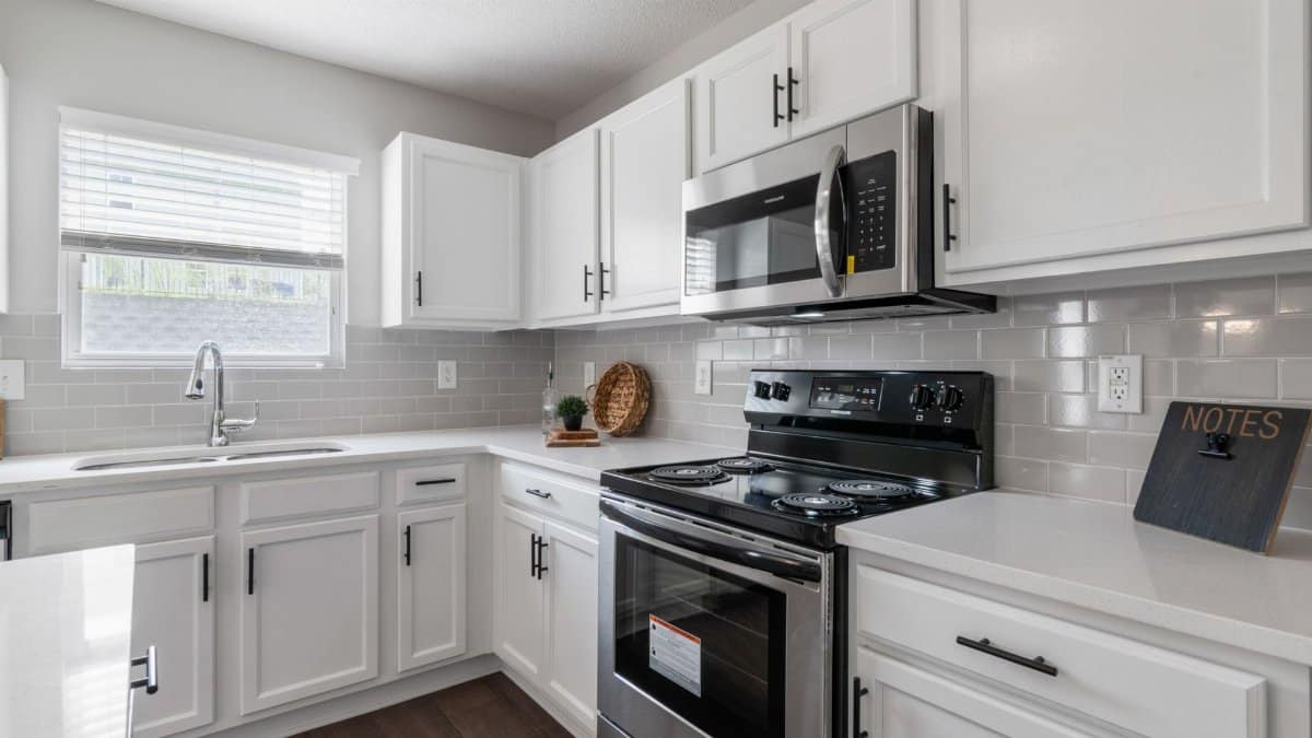 Bright white kitchen with modern stainless steel appliances and scandinavian design.