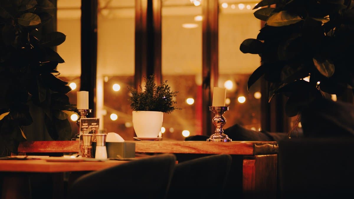 Warm and inviting restaurant table setup with candles and plants, creating a cozy atmosphere.