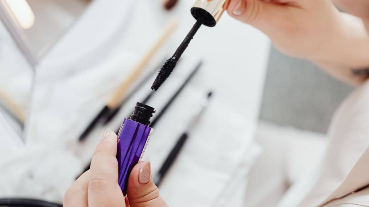 Close-up shot of hands holding and applying mascara, ideal for beauty concepts.
