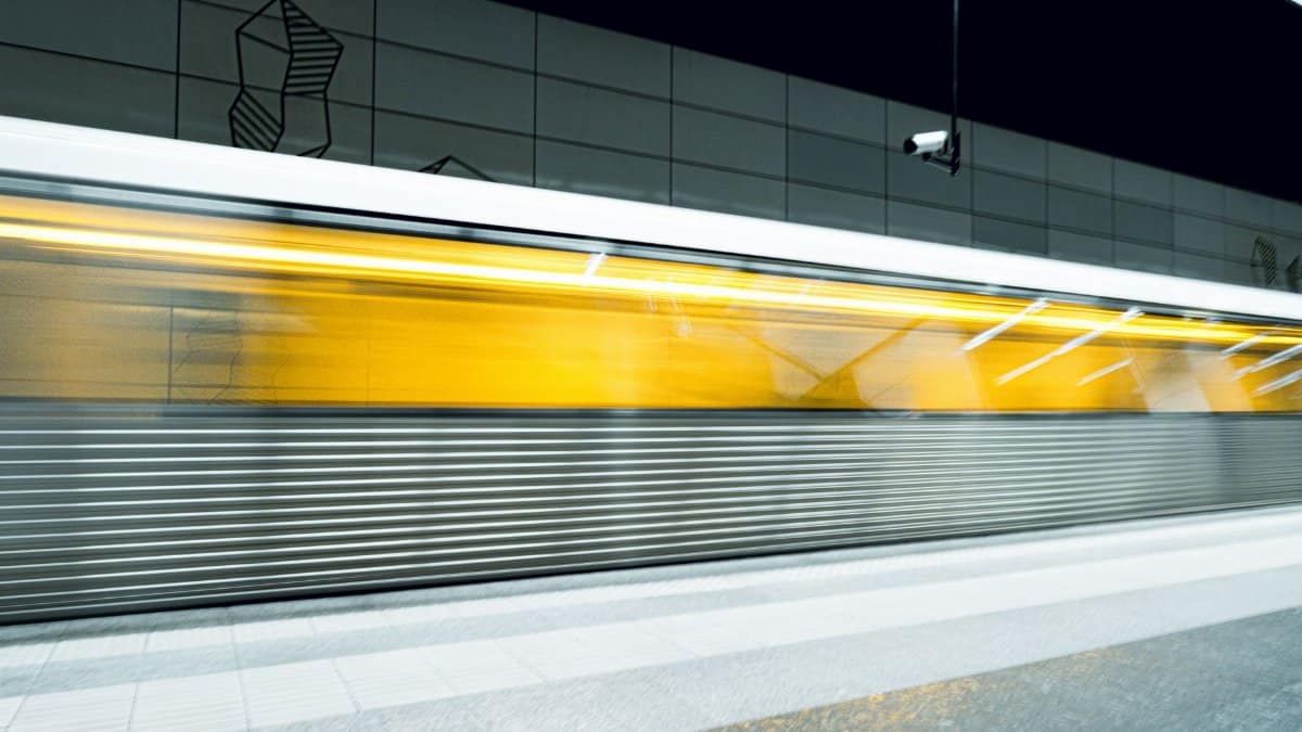 Dynamic shot of a yellow subway train in motion at a modern metro station.