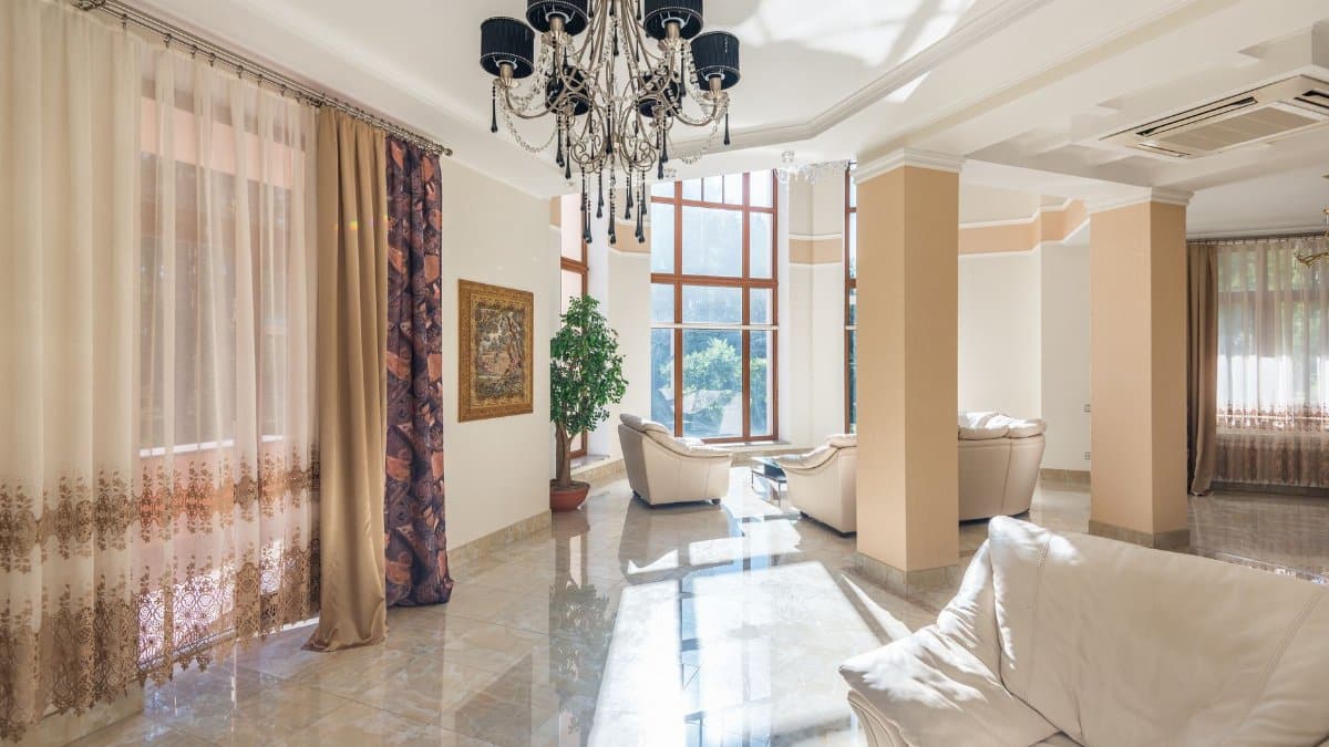 Spacious living room featuring elegant chandelier, large windows, and plush seating.