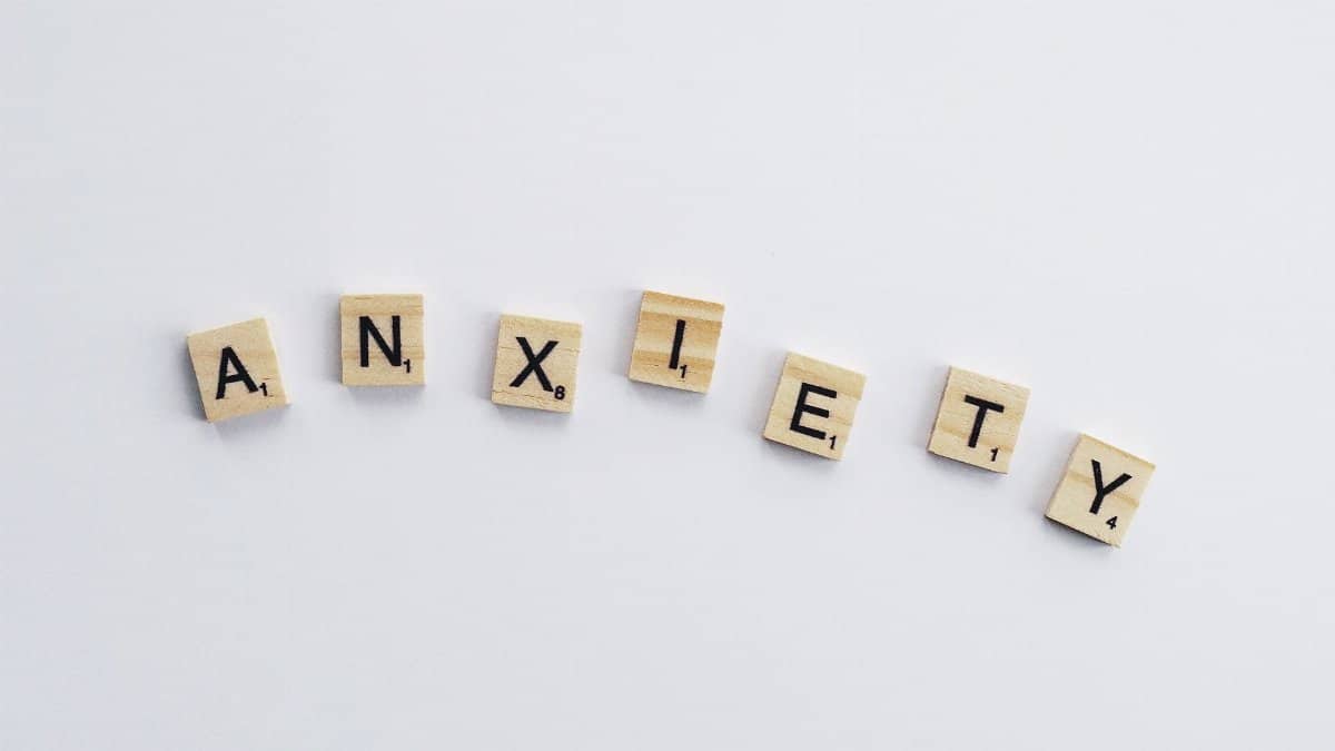 Wooden tiles on a white background spell anxiety, symbolizing mental health awareness.