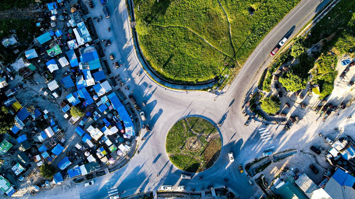 Stunning aerial photo of a bustling roundabout in Dar es Salaam, Tanzania, showcasing vibrant market life and green spaces.