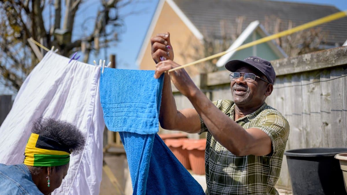 African American couple hanging colorful towels on an outdoor clothesline on a sunny day.