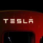 Close-up of a Tesla charging station illuminated at night, showcasing modern automotive technology.