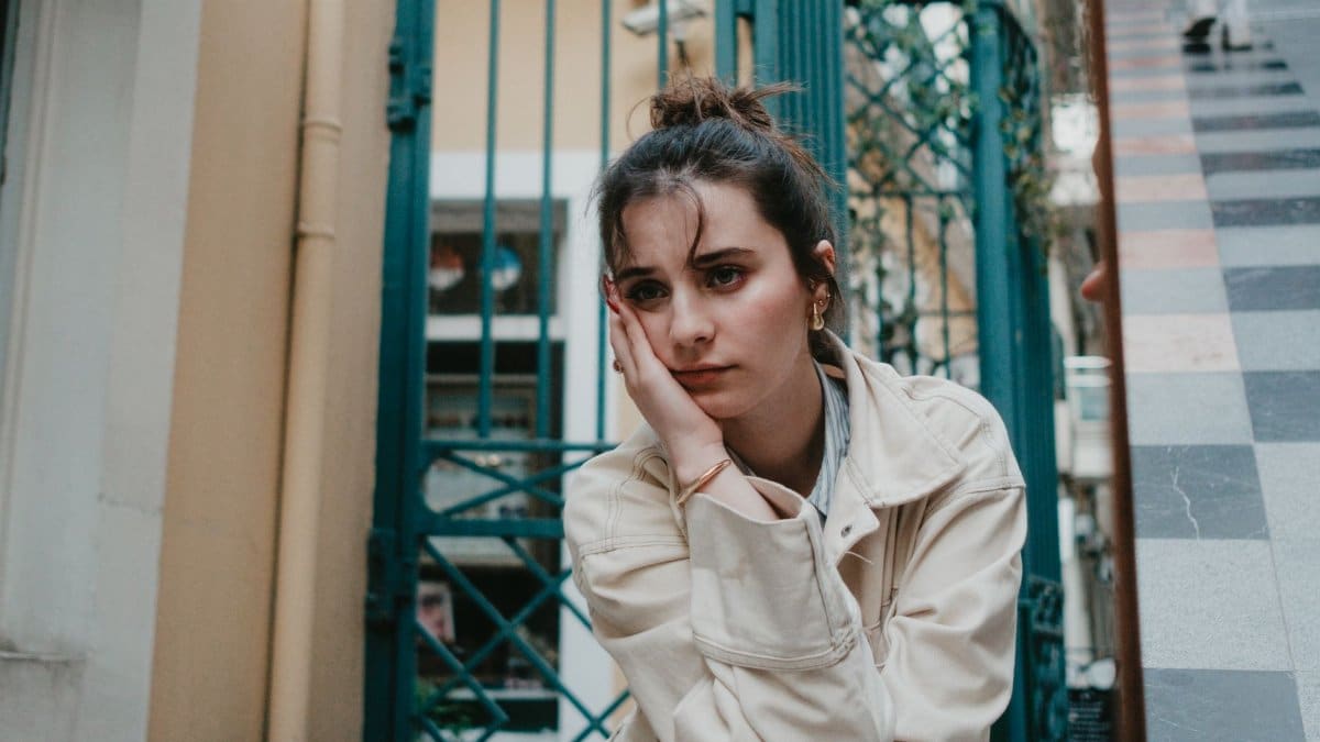 A thoughtful woman in casual attire sitting on İstiklal Street in İstanbul, Türkiye.