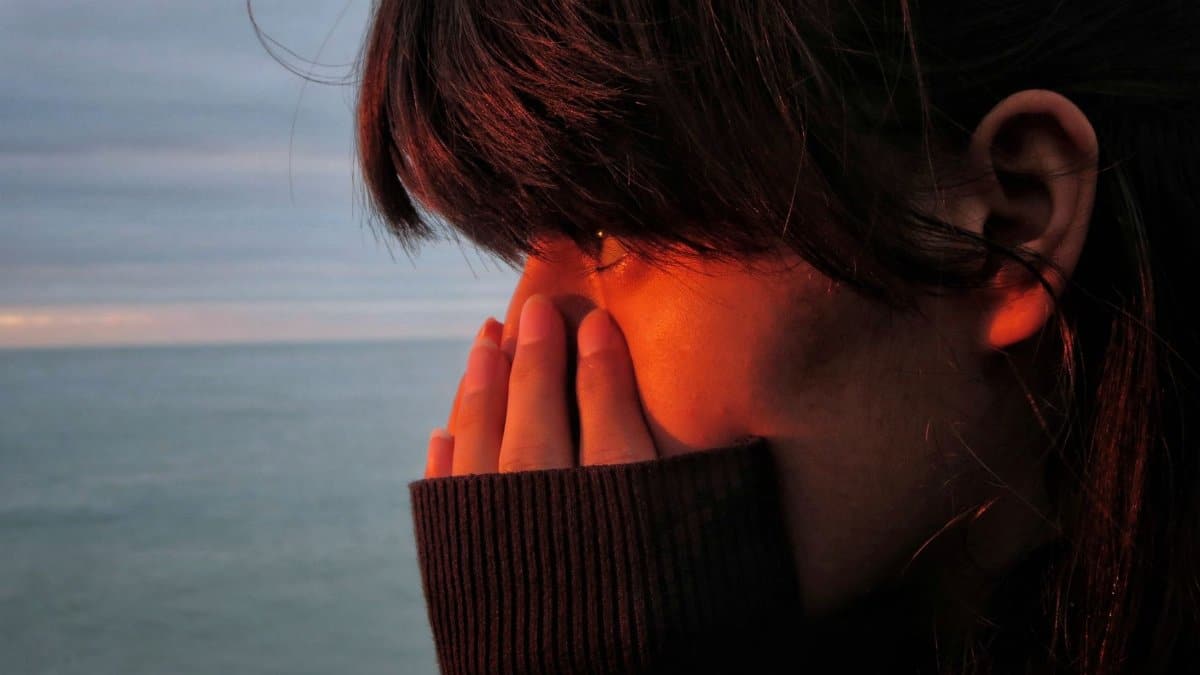 Woman in deep thought by the ocean with sunset glow in Normandy, France.