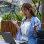 A young woman making a video call in an outdoor workspace. Flexible remote work setting.