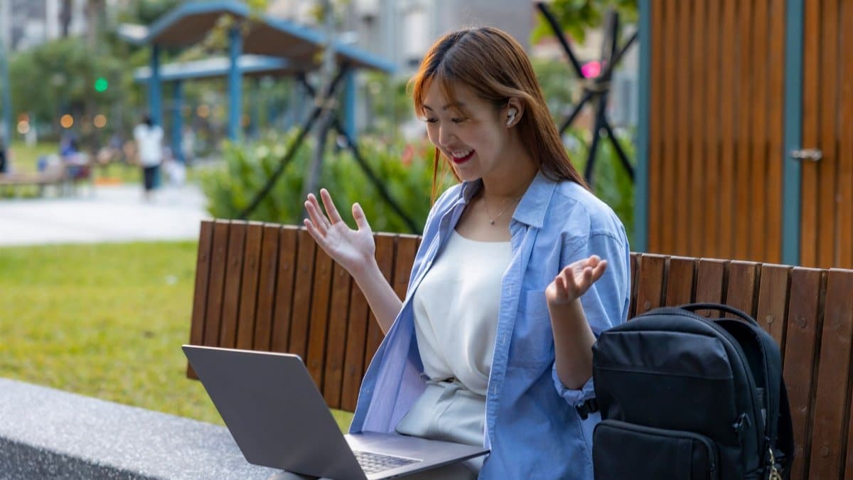 A young woman making a video call in an outdoor workspace. Flexible remote work setting.