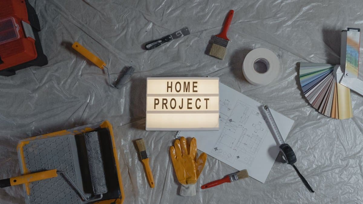 Flat lay of home improvement tools, paint samples, and blueprints for a DIY project.