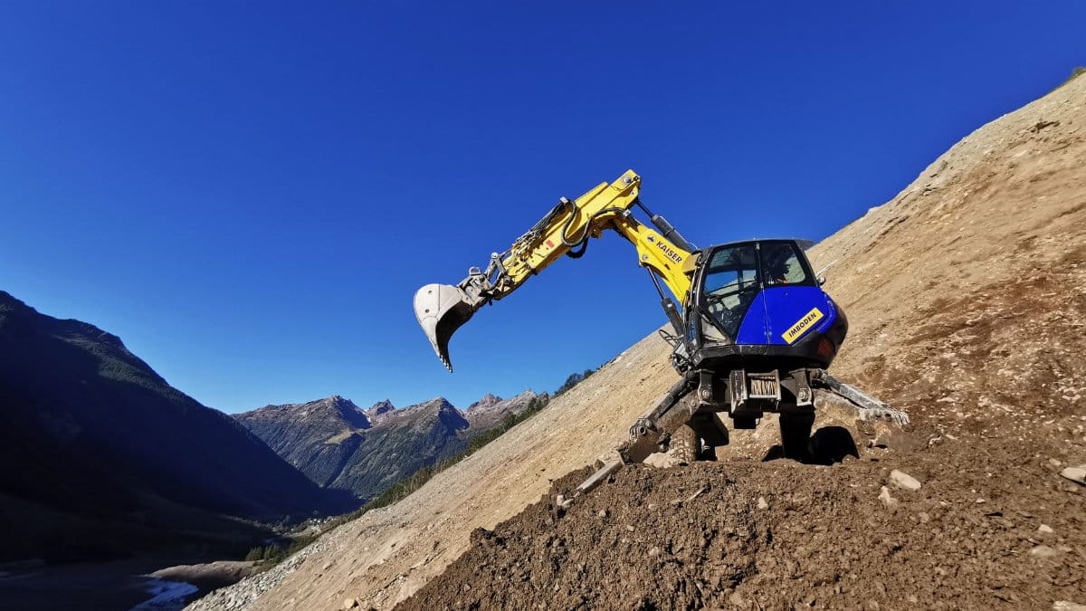 A walking excavator operates on a steep mountain slope in Blatten, Switzerland.