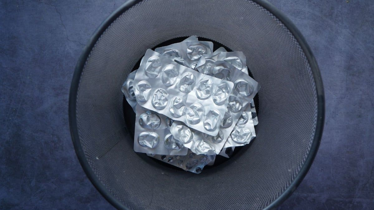 Overhead view of empty blister packs in a trash bin symbolizing waste and recycling.