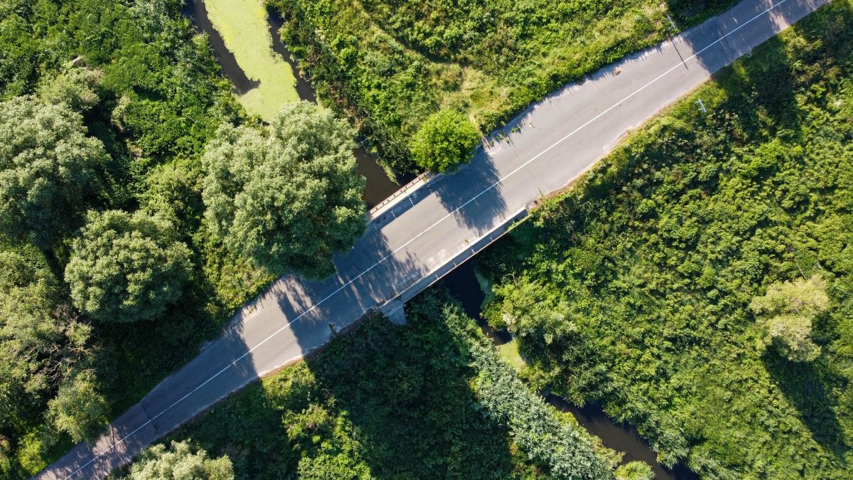 Aerial photo of a road cutting through lush greenery and waterway.