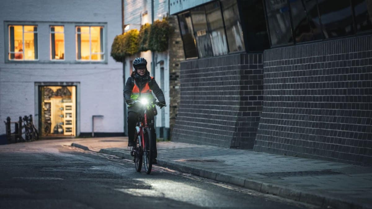 A cyclist rides through city streets at night, showcasing urban commuting safety.