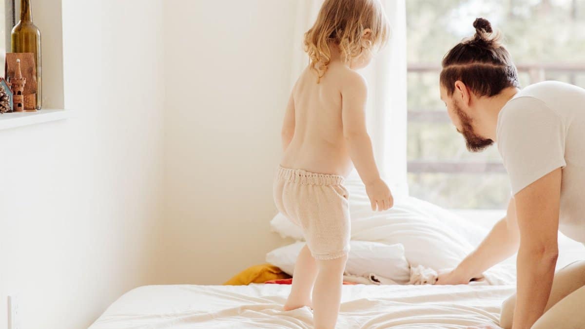 Father and toddler enjoying a cozy morning in a sunlit bedroom, creating lasting memories.