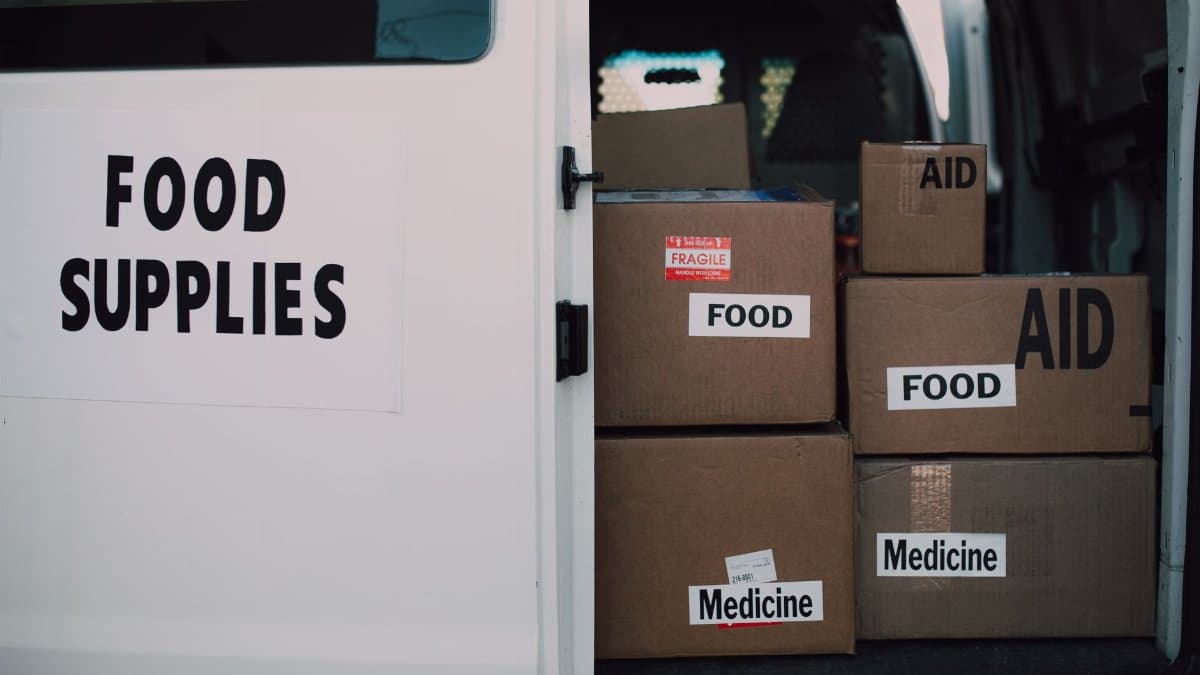 Stacked donation boxes labeled food and medicine in a delivery van for charity aid.