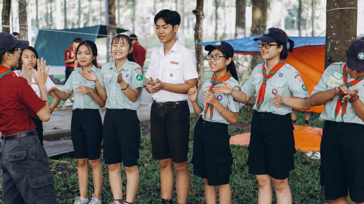 Young scouts participating in teamwork activities outdoors during a summer camp.