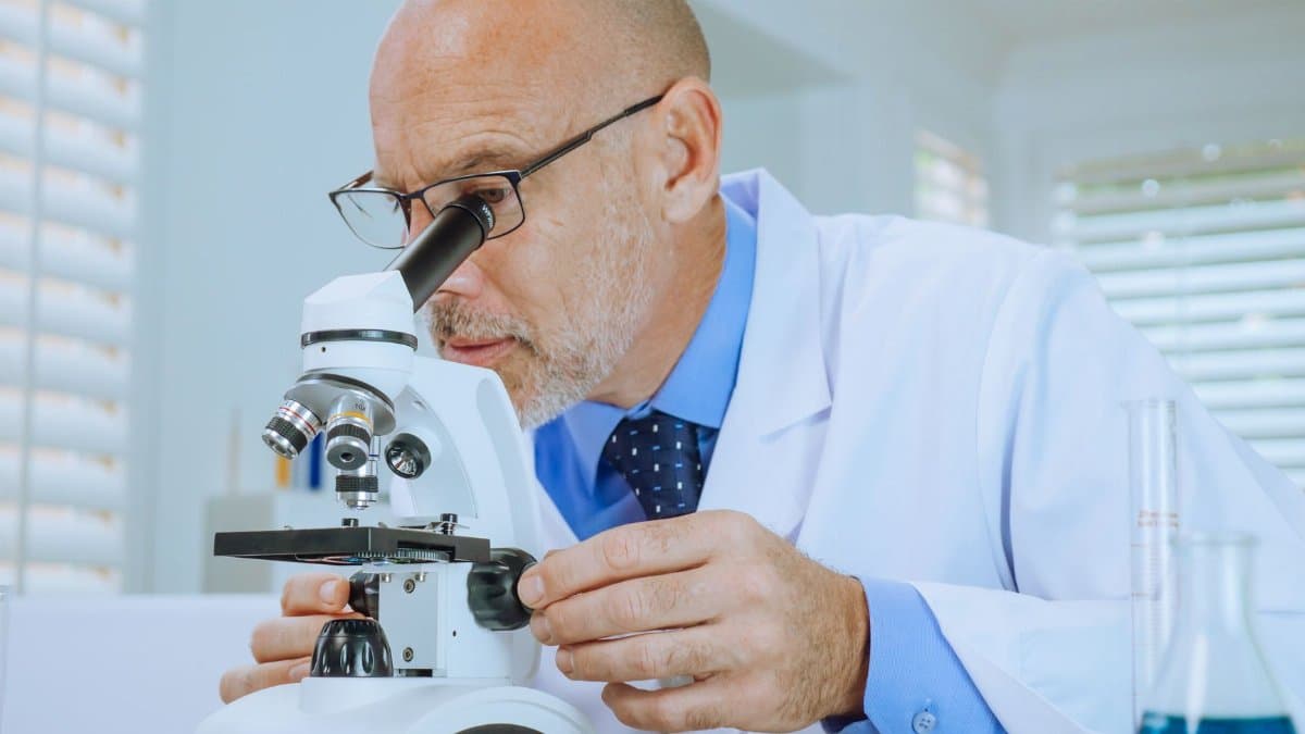 Scientist examining samples through a microscope in a modern laboratory setting.