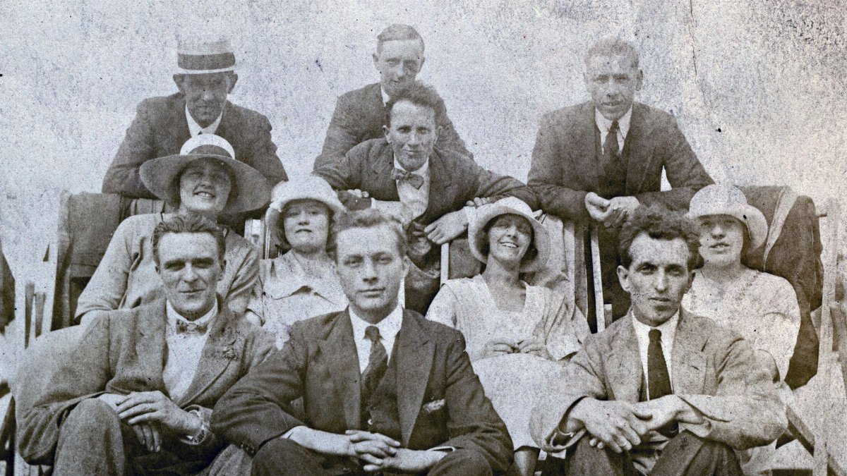 Historic black and white group photo capturing early 20th-century fashion and smiles.