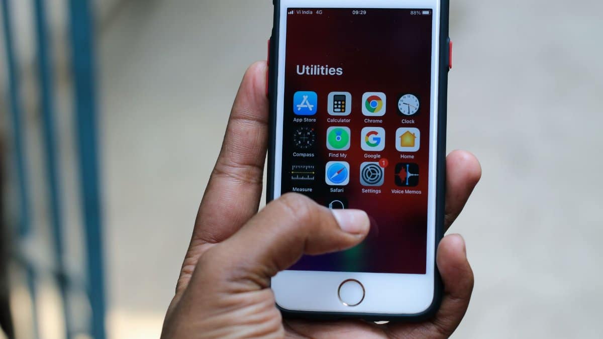 Hand holding a smartphone showing various apps in Patna, India. High detail and clarity.