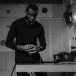 Black and white photo of a man handling a firearm at an indoor shooting range.