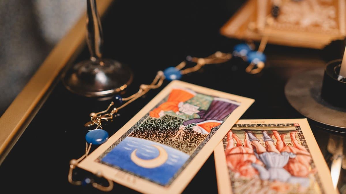 Close-up view of tarot cards on a table with a wineglass and mystical elements.