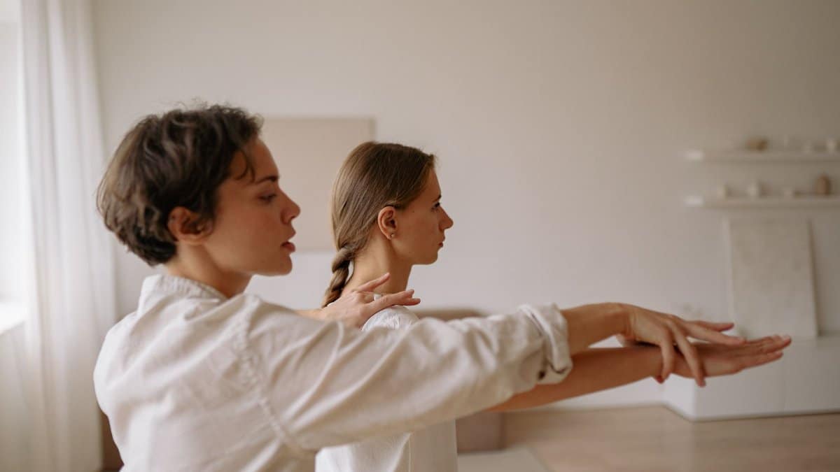 Two women practicing mindful movement exercises in a serene indoor setting.