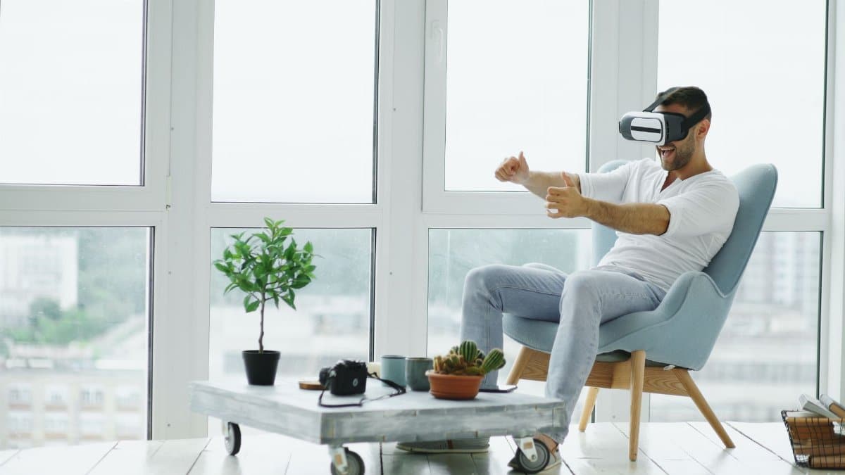 Adult male experiencing virtual reality with VR headset in a modern living room.