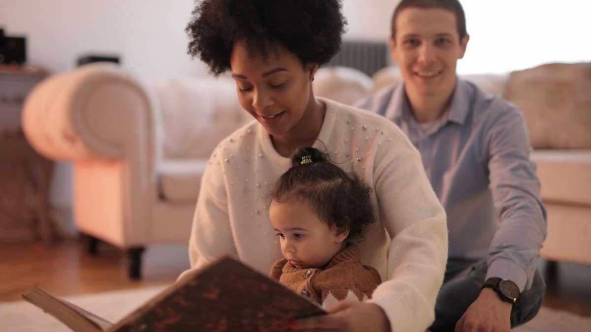 A loving family shares a special moment reading a book together indoors.